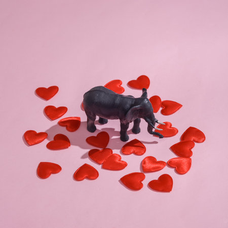 Plastic elephant with hearts on pink background. Love concept, valentine's day, february 14th celebration, creative layoutの写真素材