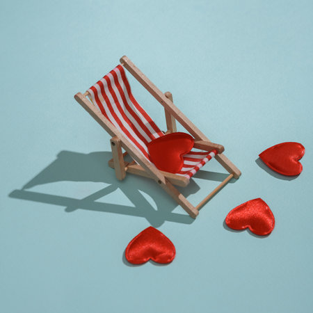 Deck chair with hearts on blue background. Love concept, valentine's day, february 14th celebration, summer rest, creative layoutの写真素材