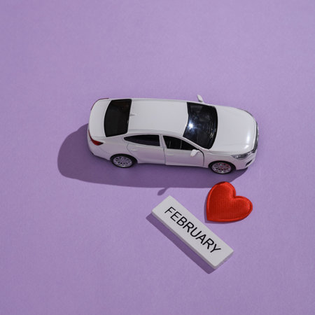 Valentine's Day, February 14th. Toy car, Wooden Tablet with the inscription february and a heart on a purple backgroundの写真素材