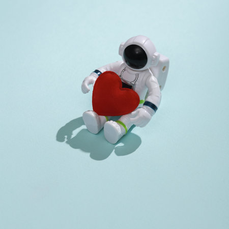 Toy astronaut with heart on blue background. Love concept, valentine's day, february 14th celebration, creative layoutの写真素材