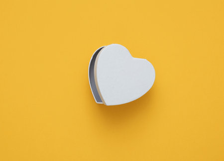 Empty white box in the shape of a heart on yellow backgroundの写真素材