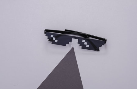 Pixelated 8 bit sunglasses on a gray background