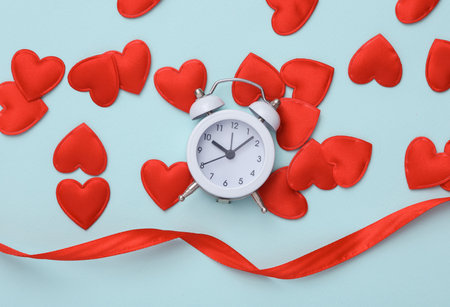 Alarm clock with hearts on a blue background. Valentine's Day. top viewの写真素材