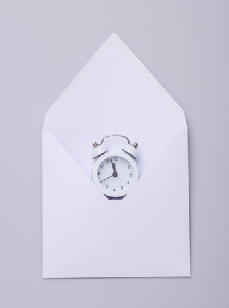White Envelope with alarm clock on a gray background.の写真素材