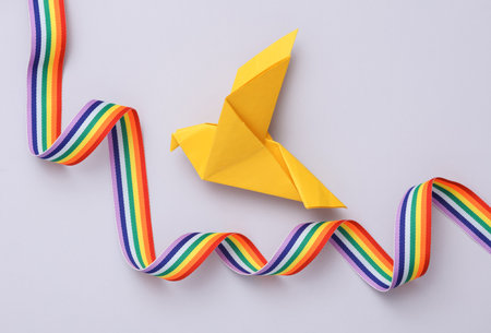 Yellow origami dove with rainbow ribbon on a gray background. Peace symbol, no warの写真素材