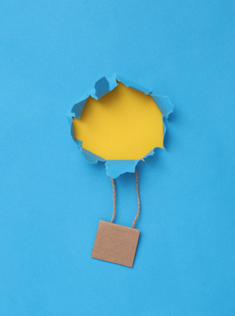 children's creativity. Flying hot air balloon on a blue background with torn hole. dream conceptの写真素材