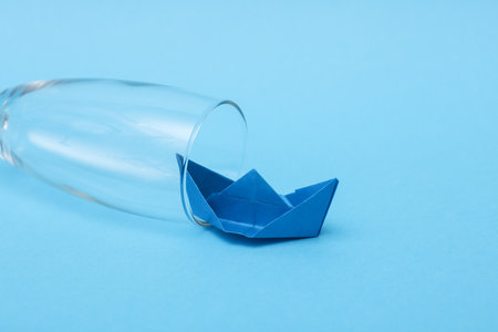 Glass with a paper boat on a blue background. alcohol treatmentの写真素材