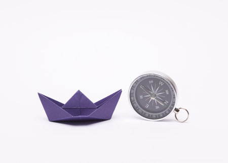 Leadership, pursuit of goals, navigation, business concept. Paper boat and compass on a blue backgroundの写真素材