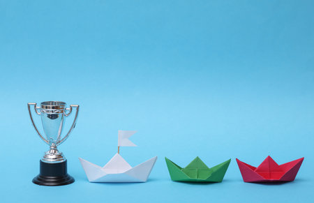 paper boats and winner's cup on a blue background. The concept of competition, leadersの写真素材