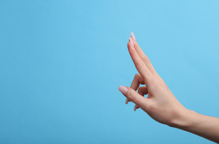 Female hand mockup holding empty space for holding business card on blue backgroundの写真素材