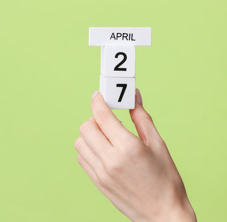 Block calendar with date april 27 in female hand on green backgroundの写真素材