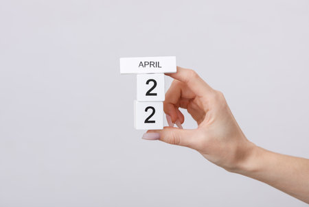 Block calendar with date april 22 in female hand on gray backgroundの写真素材
