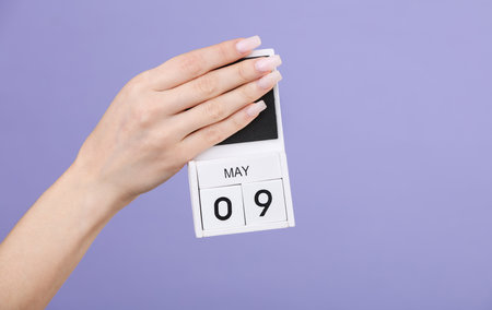Block calendar with date may 09 in female hand on pastel lavender color backgroundの写真素材
