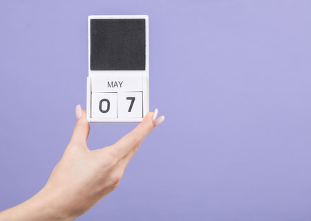 Block calendar with date may 07 in female hand on pastel lavender color backgroundの写真素材
