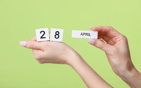 Block calendar with date april 28 in female hands on green backgroundの写真素材