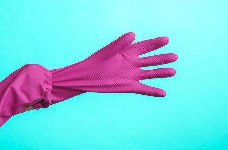 Hands wear purple rubber cleaning gloves on a purple background. House cleaning and housekeeping conceptの写真素材