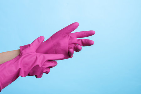 Hands wear purple rubber cleaning gloves on a purple background. House cleaning and housekeeping conceptの写真素材