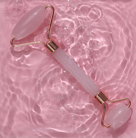 Jade massage roller in pink water with shadows. top viewの写真素材