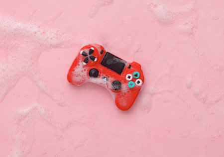 Toy gamepad in foam on pink background