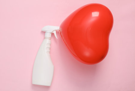 Red heart-shaped air balloon with detergent bottle on pink background. Valentine's Day. creative layoutの写真素材