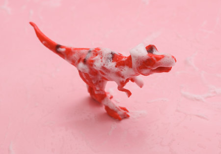 Toy tyrannosaurus rex in foam on a pink backgroundの写真素材