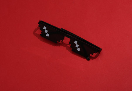 8 bit pixel sunglasses on a red background with a shadow. minimalist style.の写真素材