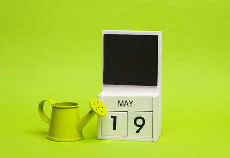 Calendar with date may 19 with miniature watering can on green background