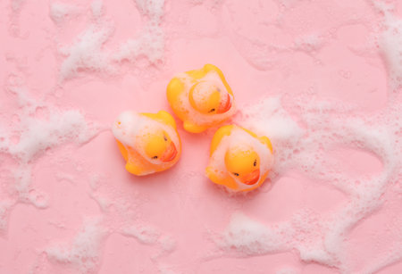 Rubber ducklings with foam on a pink backgroundの写真素材