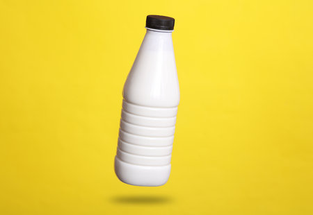 yogurt bottle levitates on a yellow background with a shadowの写真素材
