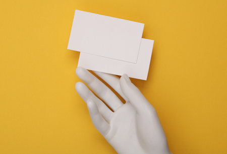 Hand holding Many blank business cards for branding on yellow background. Mockup for presentations and corporate identityの写真素材