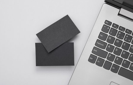 Two black Blank business cards for branding and laptop on gray background. top view. business conceptの写真素材