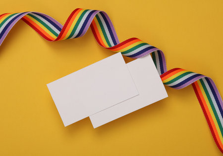 White blank business cards for branding with lgbt rainbow ribbon on yellow background. Mockup for presentations and corporate identityの写真素材