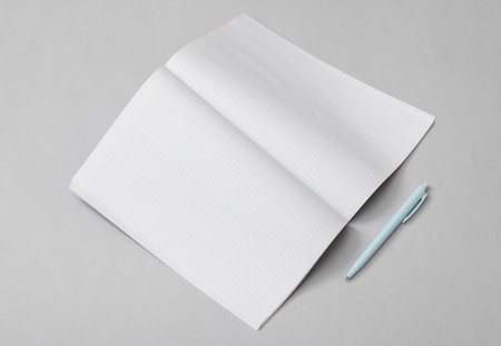 Open Notebook (exercise book) or journal (magazine) with white papers and pen on gray background....