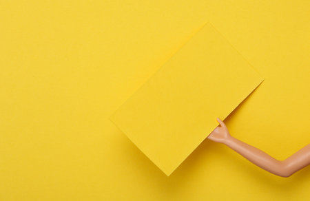 Yellow Blank business card for corporate identity in doll hand on yellow background. creative mockupの写真素材