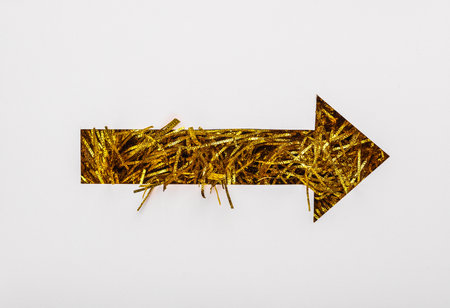 Index arrow cut out of paper hole with golden tinsel on white backgroundの写真素材