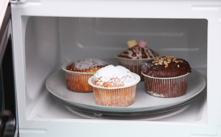 Appetizing cupcakes on a plate inside the microwaveの写真素材
