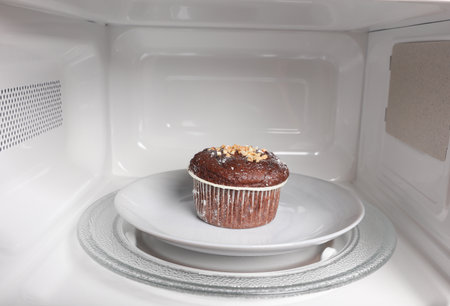 Delicious cupcake on plate inside a microwave oven close-upの写真素材