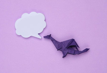 Origami dragon with speech bubble on purple background. Symbol of the yearの写真素材
