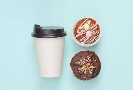 Takeaway coffee cup with cupcakes on blue background. top viewの写真素材