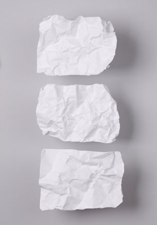 White crumpled piece of papers on gray background