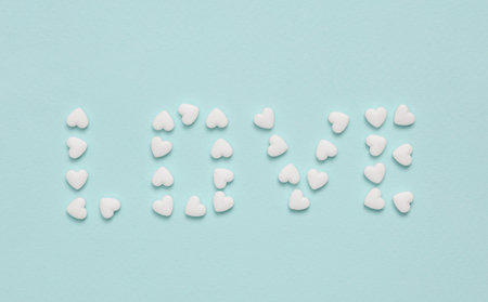 Word love laid out with heart shaped pills on a blue background. Medicine, love conceptの写真素材