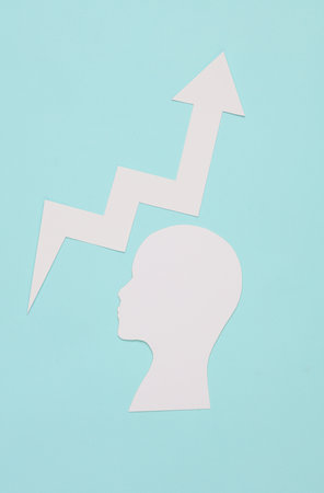 personal growth. Head silhouette with growth arrow cut out of paper on a blue backgroundの写真素材