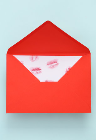 Lip print left by lipstick on white paper in red envelope on blue pastel background. Valentine's day concept. top viewの写真素材