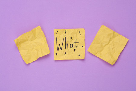 Crumpled memo paper with the question what on a purple background