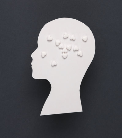 Metal health, love, medicine concept. Paper-cut silhouette of a human head with heart-shaped pills on a gray background.の写真素材
