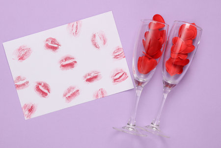 Lip print left by lipstick on white paper and glasses with hearts on pastel purple background. Valentine's day concept. top viewの写真素材