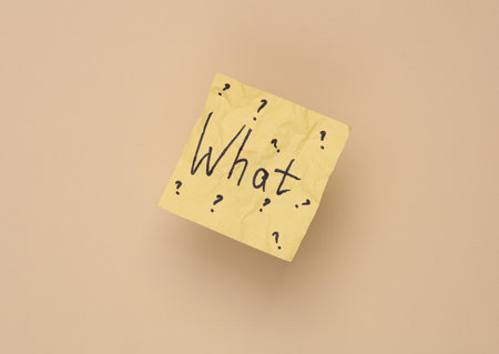 Crumpled memo paper with the question what on a beige background