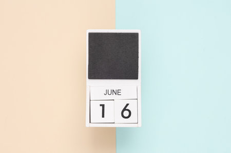 White wooden calendar with the date june 16 on a blue beige background. top viewの写真素材