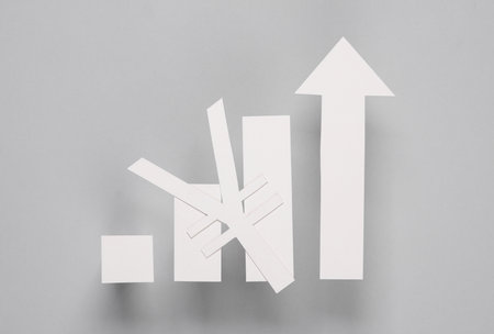 Paper-cut columns of a chart tending upwards and yuan symbol on a gray background. Analytics, business conceptの写真素材