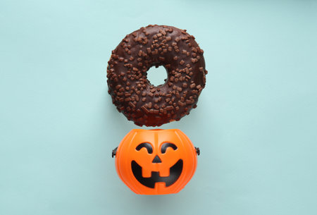 Chocolate donut and halloween bucket on blue background. Halloween concept. Trick or Treatの写真素材